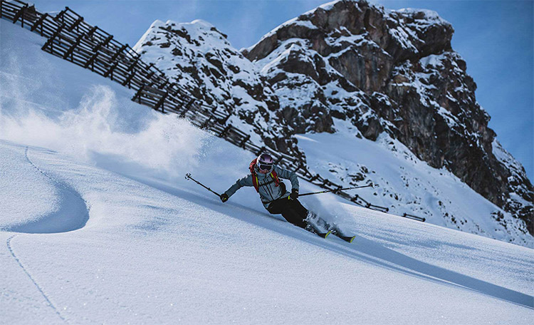 Een freerider skiet buiten de piste in de diepe sneeuw.