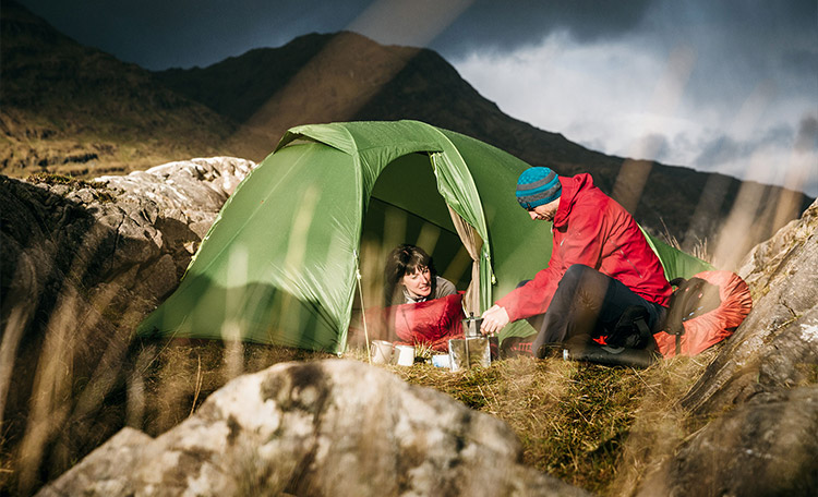 Man en vrouw zitten bij zonnig weer in een tent en lachen naar elkaar